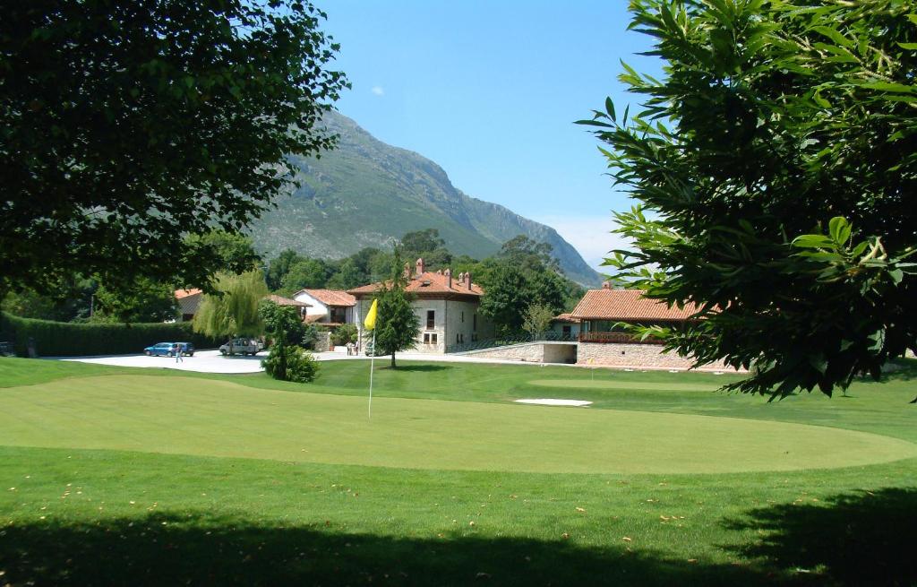 a golf course with a house and a golf green at Hotel Aldama Golf in Quintana de Llanes