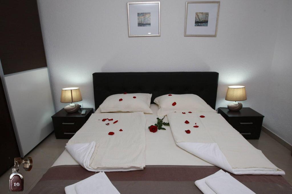 a bedroom with a bed with white sheets and red flower pillows at Villa Andjelina in Budva