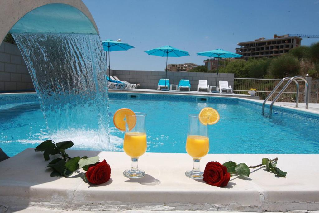 two glasses of orange juice on a table next to a swimming pool at Villa Andjelina in Budva