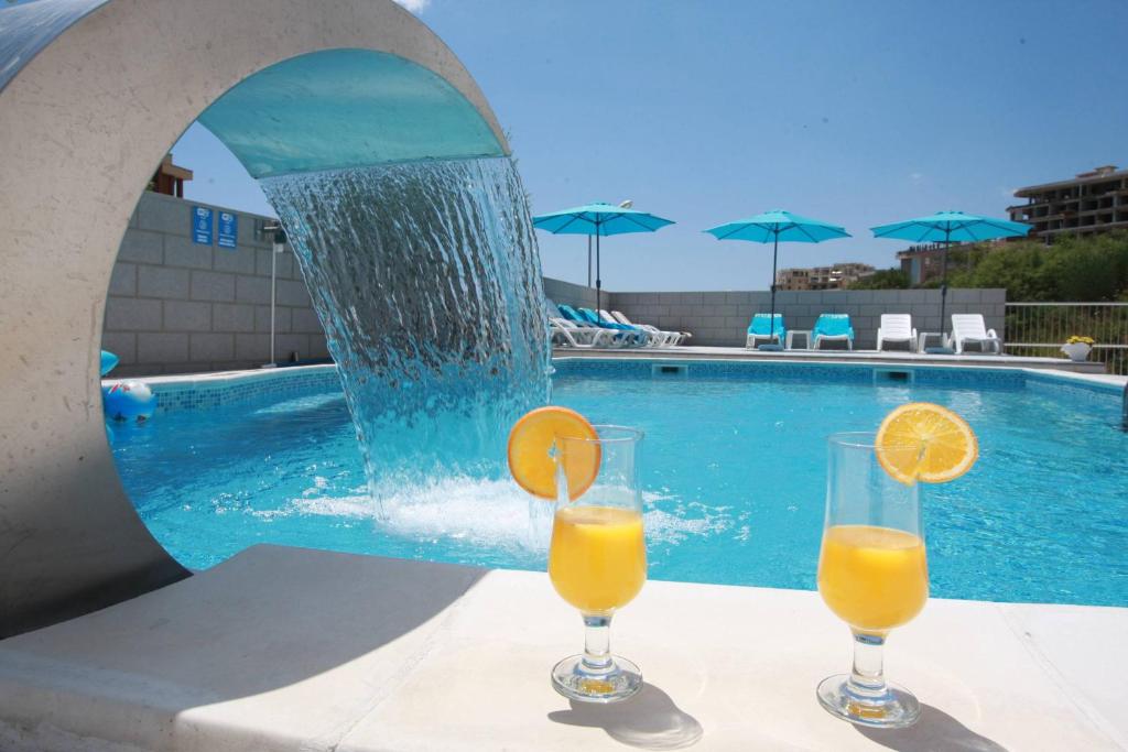 two glasses of orange juice sitting on a table next to a pool at Villa Andjelina in Budva