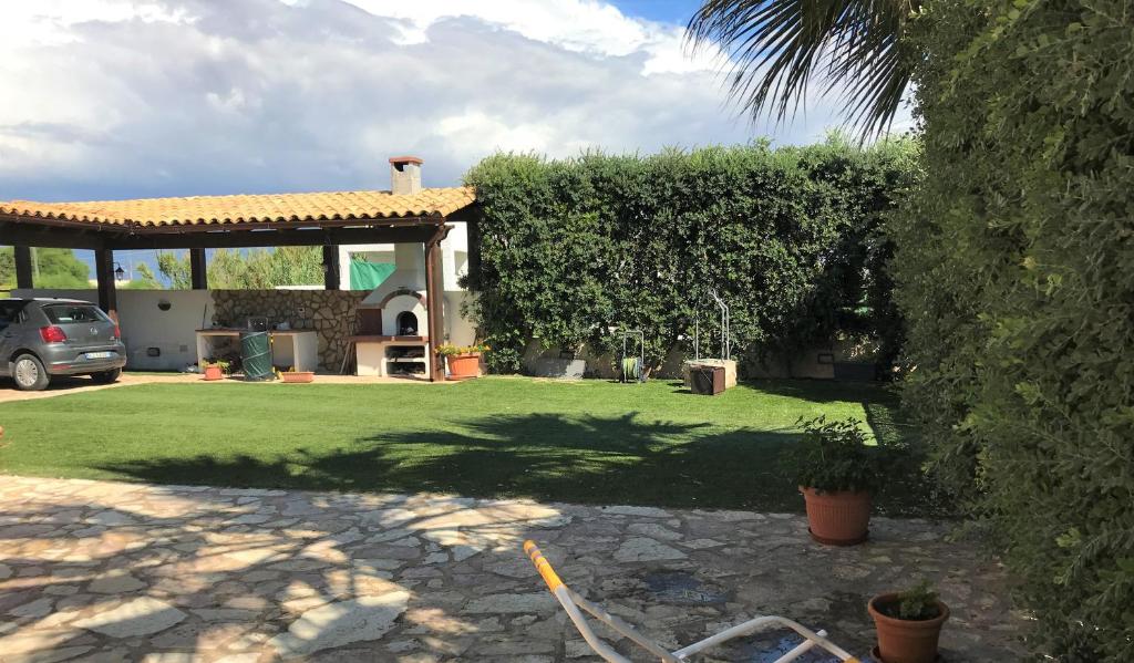 een tuin met een huis met een grote heg bij Posidonia Apartments in Marsala