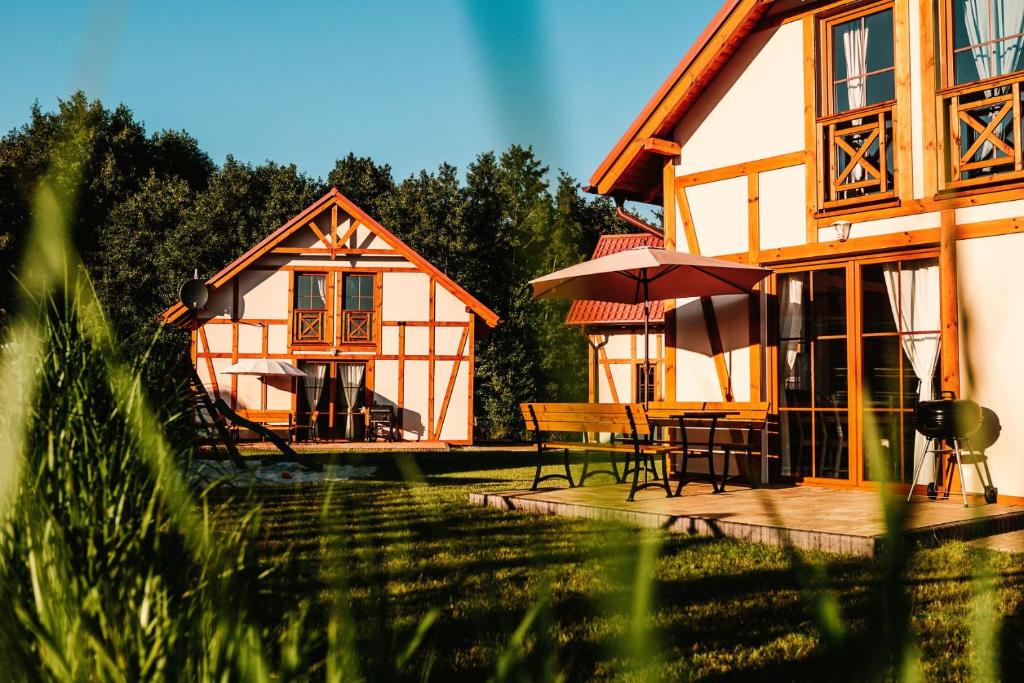 ein Haus mit einem Tisch und einem Sonnenschirm davor in der Unterkunft Kubiczówka in Kopalino