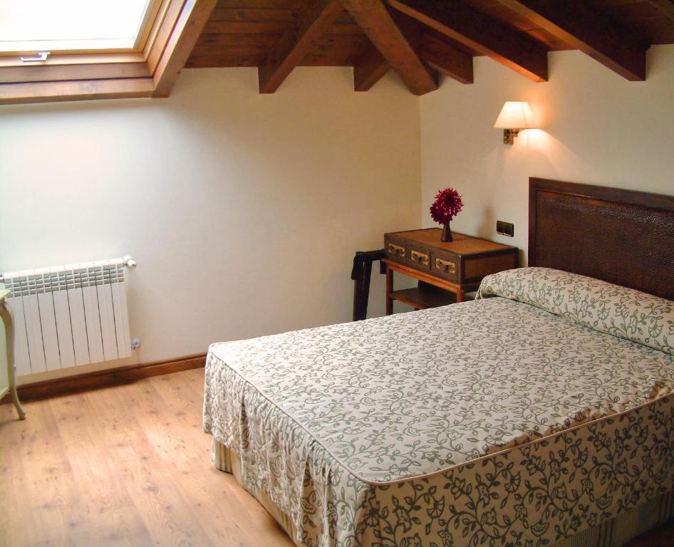 a bedroom with two beds and a table and a window at Hotel Aldama Golf in Quintana de Llanes