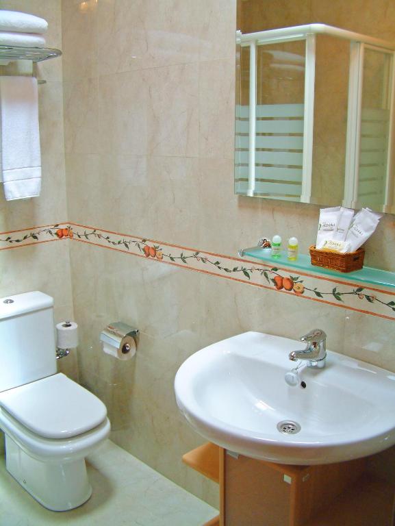 a bathroom with a sink and a toilet and a mirror at Hotel Aldama Golf in Quintana de Llanes