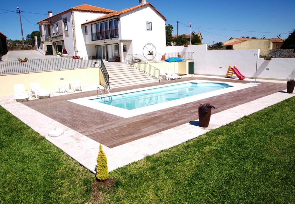 una piscina con terraza de madera y una casa en Villa Barq, en Barcelos