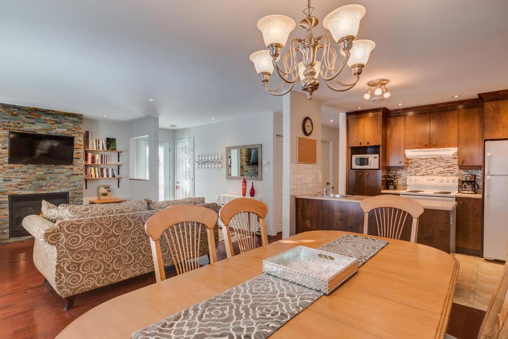 a kitchen and living room with a table and chairs at Condo Entre Ville/Nature in Magog-Orford