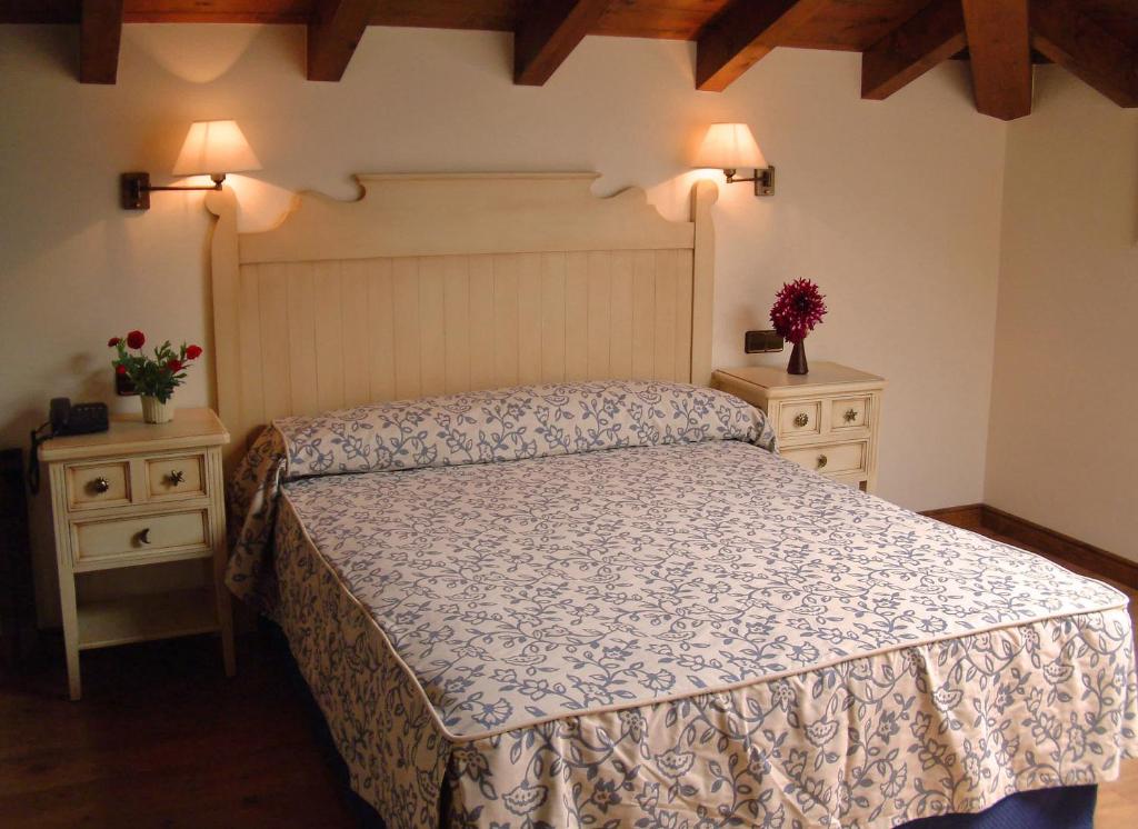 a bedroom with a bed and two night stands with flowers at Hotel Aldama Golf in Quintana de Llanes