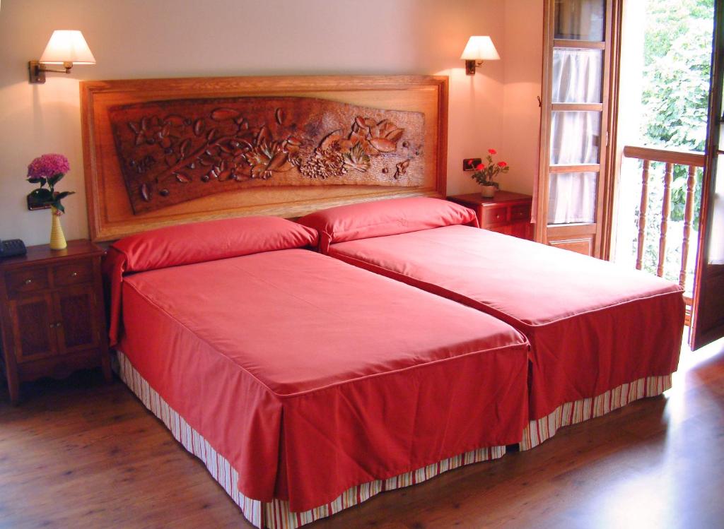 a bedroom with a large bed with red sheets at Hotel Aldama Golf in Quintana de Llanes