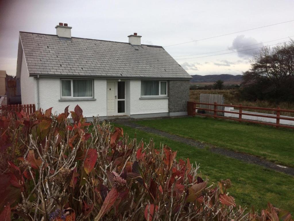 ein weißes Haus mit einem Zaun und einem Hof in der Unterkunft Teach Barney in Falcarragh