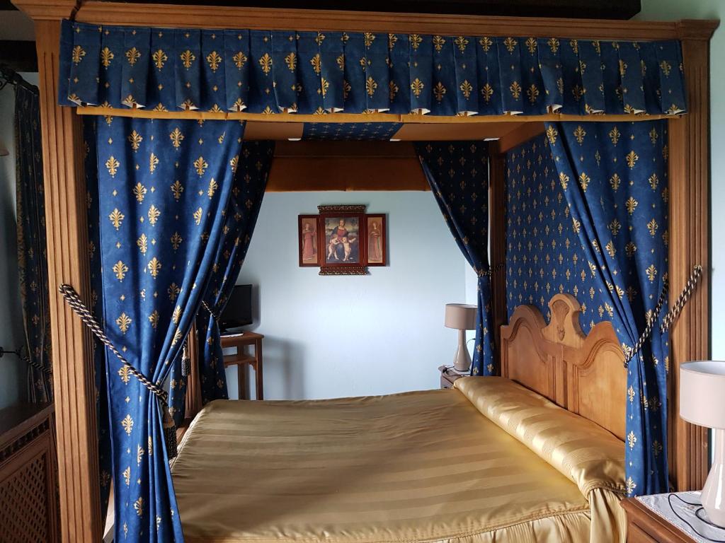 a bedroom with a canopy bed with blue curtains at Hotel Posada Real in A&iacute;nsa