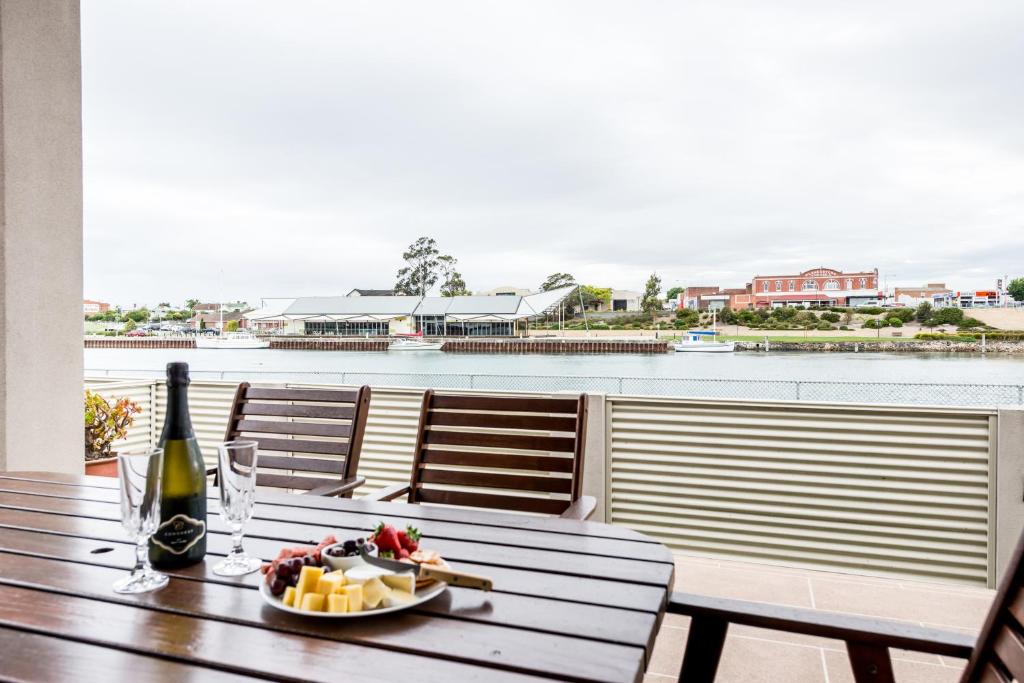 a table with a plate of food and a bottle of wine at Leven River Retreat in Ulverstone
