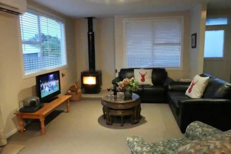 a living room with a couch and a tv at Walnut Cottage, Turangi/Tongariro in Turangi