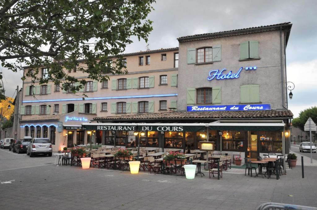 a hotel with tables and chairs in front of a building at Grand Hôtel du Cours in Sisteron