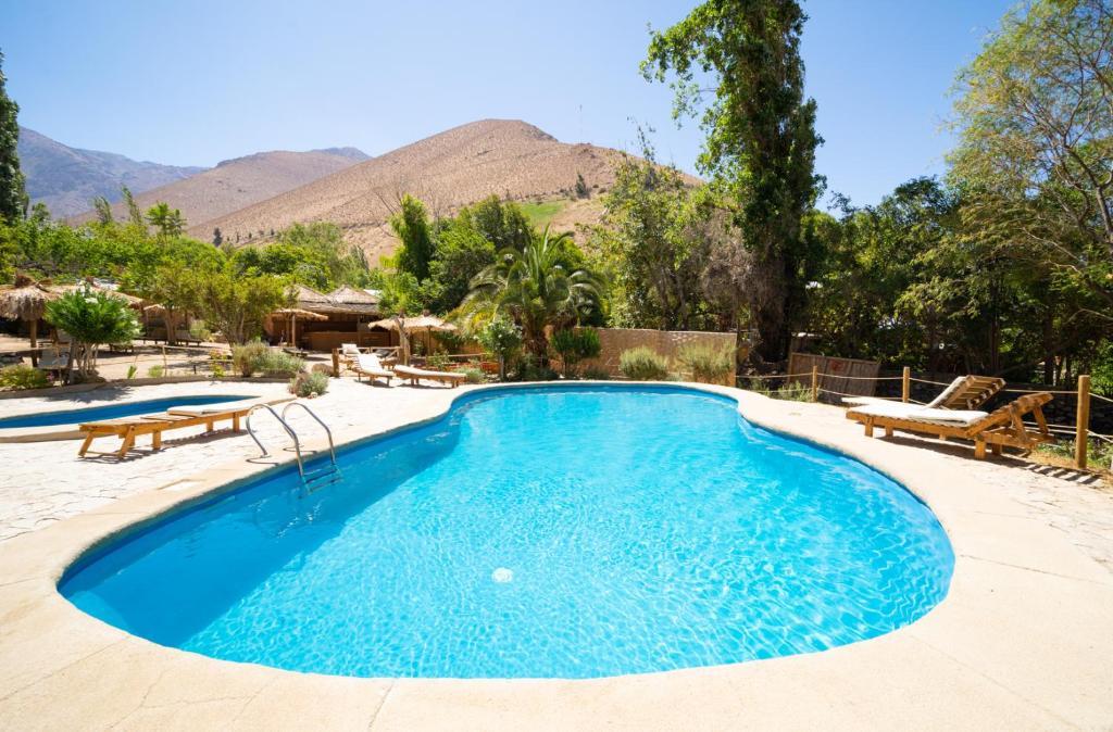 a swimming pool in a resort with mountains in the background at Hotel El Tesoro de Elqui in Pisco Elqui