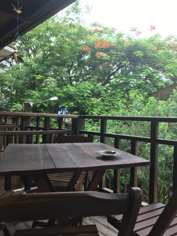 einen Holztisch und Stühle auf einer Terrasse mit einem Baum in der Unterkunft Buganville Loft in Abraão