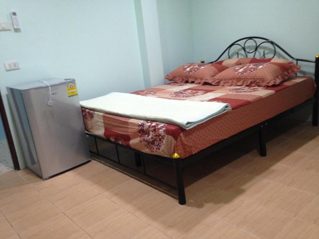 a bed next to a refrigerator in a room at J&E in Nong Prue
