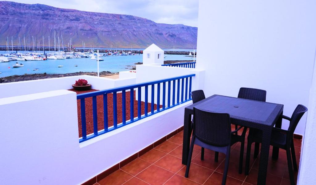 uma varanda com uma mesa e cadeiras e vista para um porto em La Graciosa Punta Caracol em Caleta de Sebo