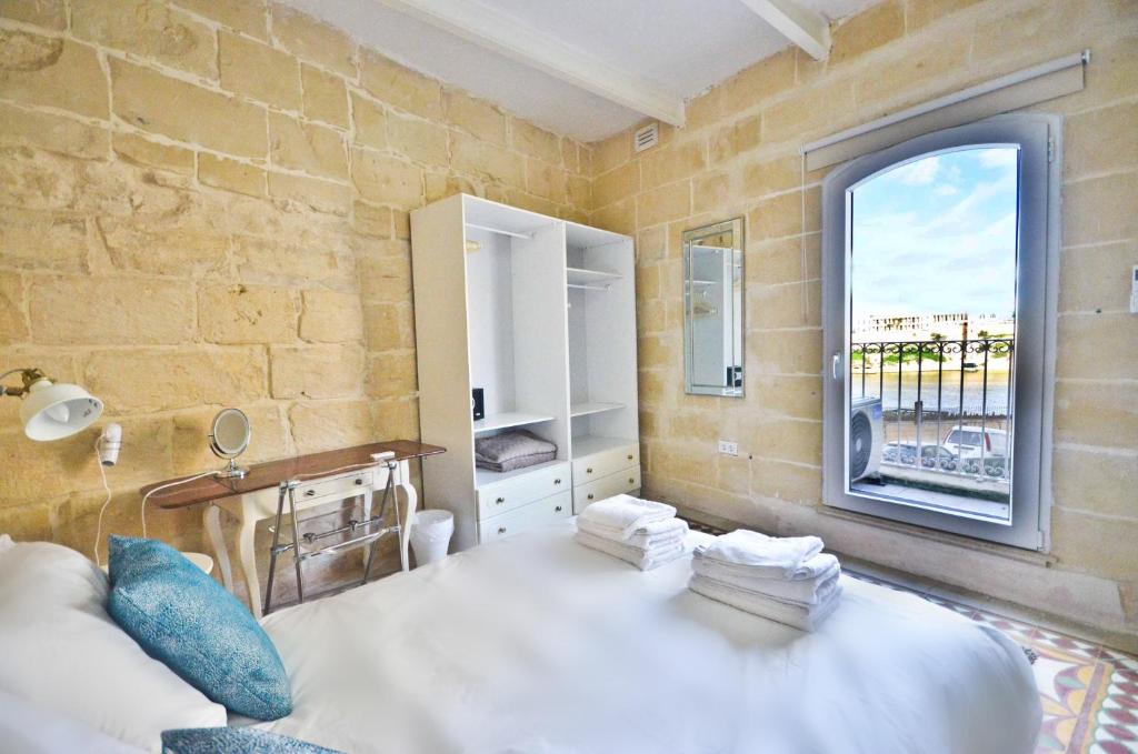 um quarto com uma grande cama branca e uma janela em Eight Point Living 6B em Birgu