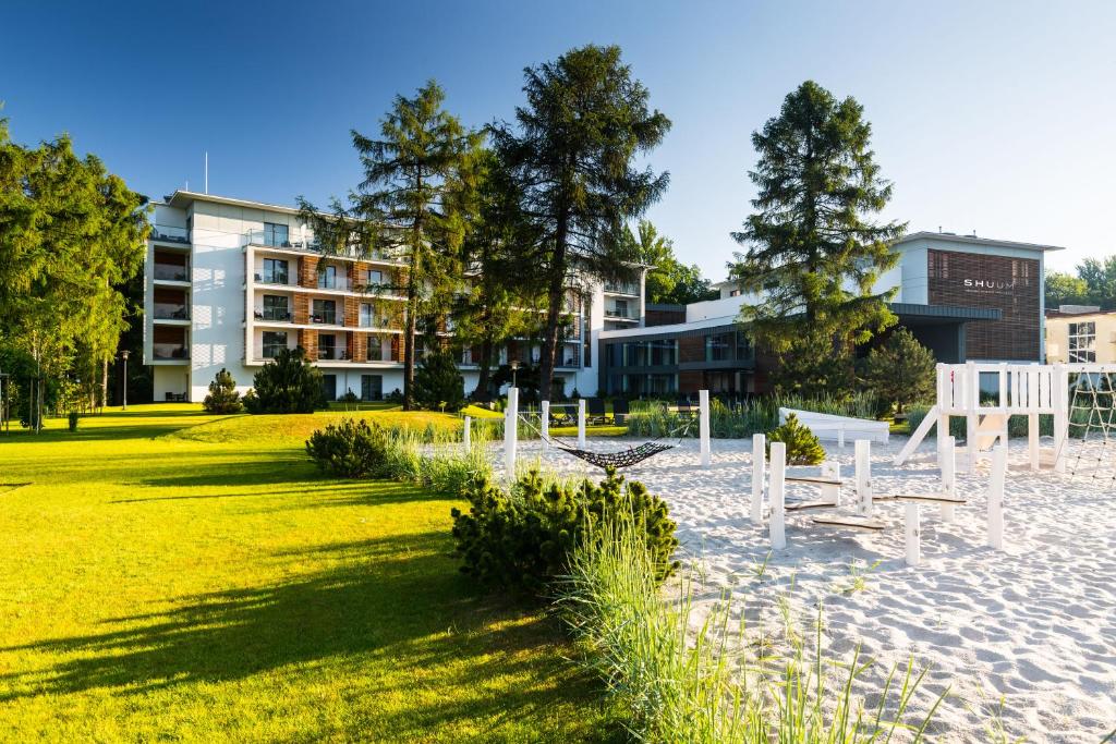 a park with white chairs and a building at Shuum Boutique Wellness Hotel in Kołobrzeg