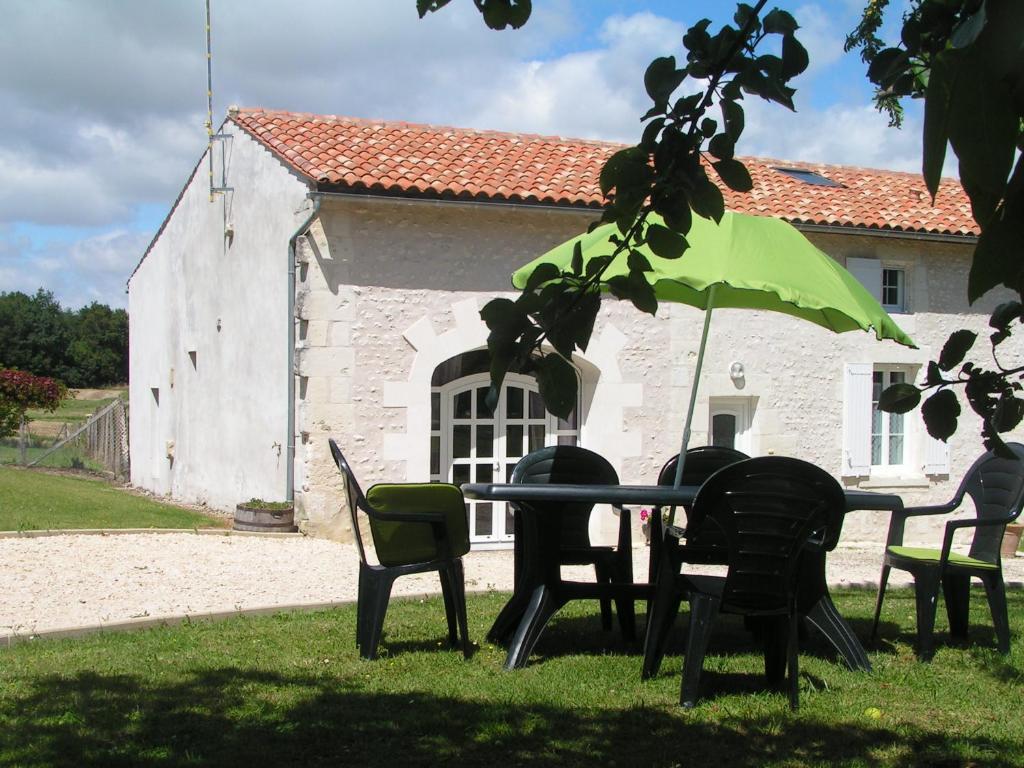 einem Tisch mit Stühlen und einem Regenschirm vor einem Gebäude in der Unterkunft la maison d'Amélie in Saint-Fort-sur-Gironde