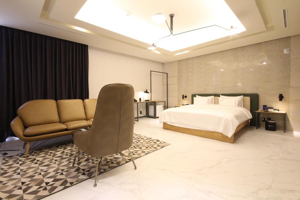 - une chambre avec un lit, un canapé et une chaise dans l'établissement Hotel Eco stay, à Jeonju