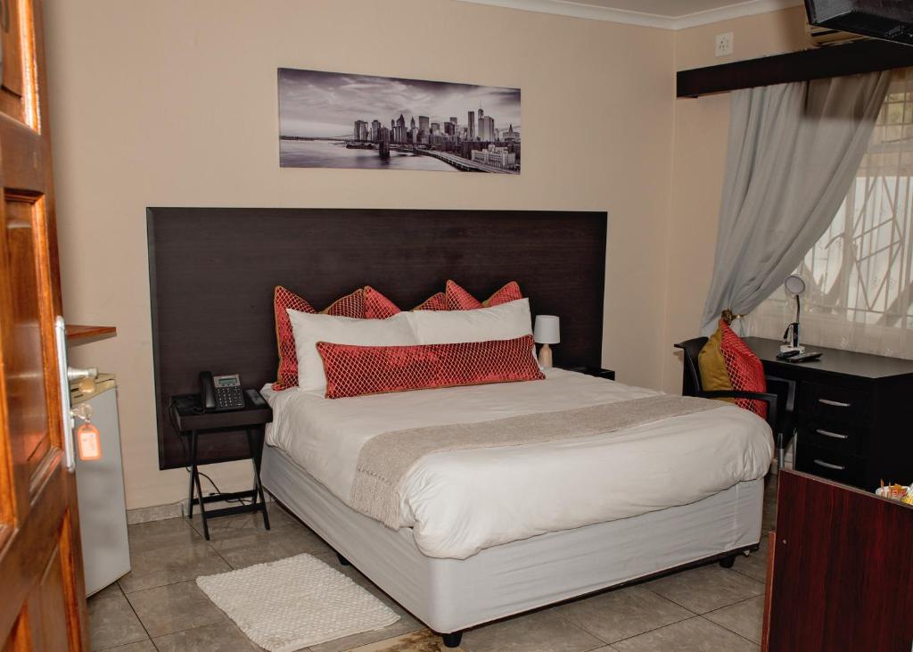 a bedroom with a large bed with red pillows at Savannah Guest House in Polokwane