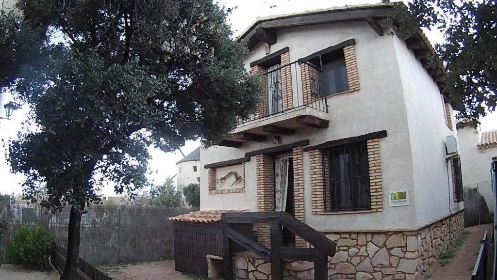una gran casa blanca con un árbol delante en Casa Rural La Ossa en Ossa de Montiel