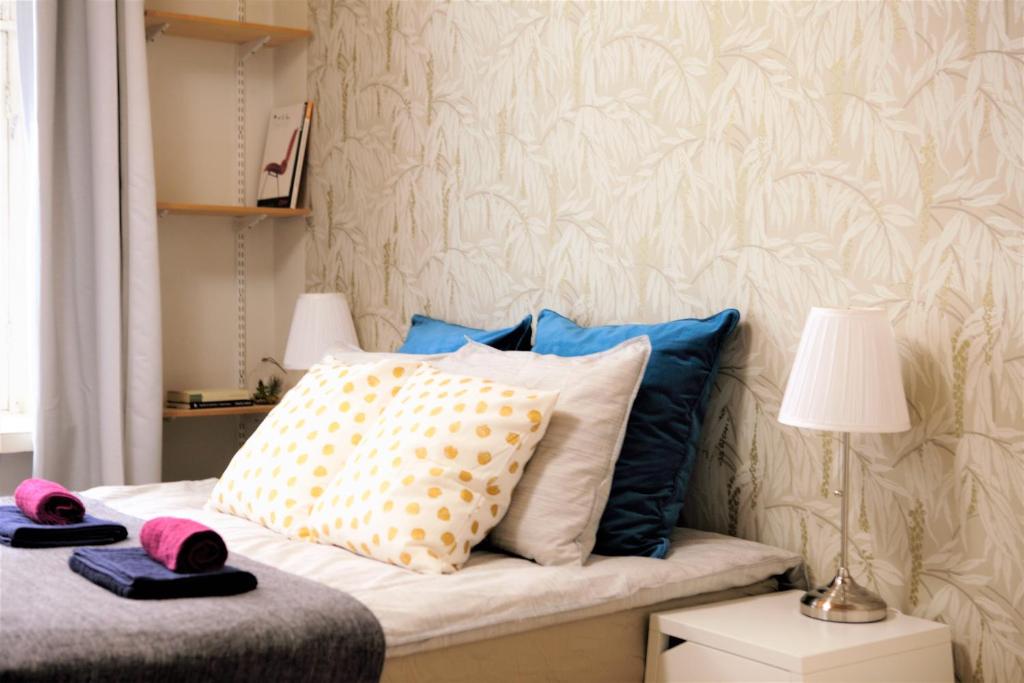 1 dormitorio con 1 cama con almohadas y lámpara en Stay Here Apartment Liisa, en Helsinki