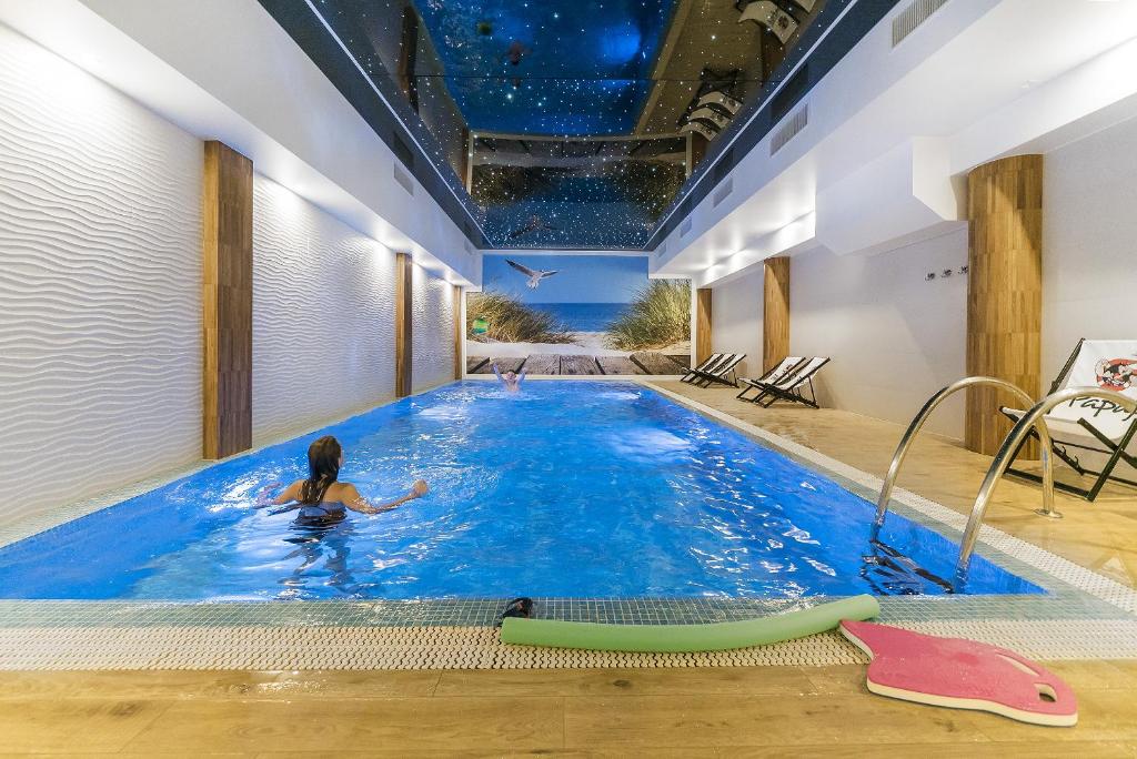 a woman swimming in a swimming pool at Papaj Resort in Jastrzębia Góra