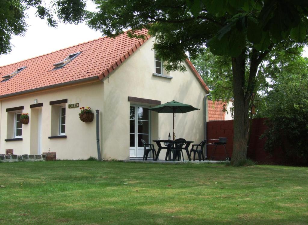 a house with a table and umbrella in the yard at Coury House, Chavasse Farm, Somme in Hardecourt-aux-Bois