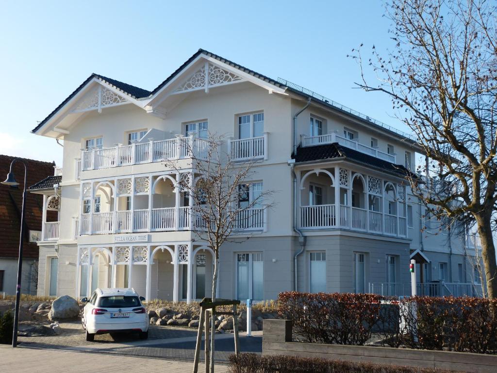 a white house with a car parked in front of it at Villa Ocean Time in Haffkrug