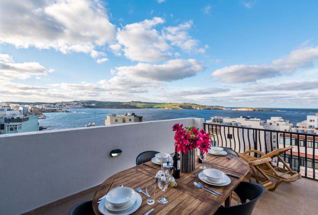 einen Tisch auf einem Balkon mit Blick auf das Wasser in der Unterkunft Seashells 2 bedroom Apartment with sunny terrace with stunning sea views - by Getawaysmalta in St Paul's Bay