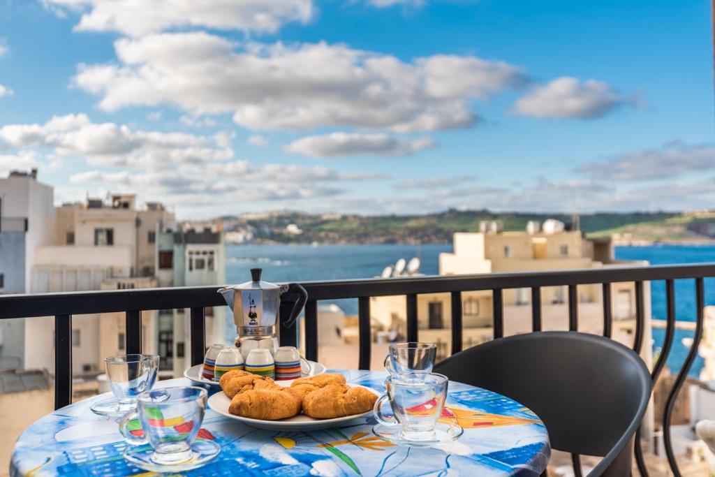 un tavolo con un piatto di cibo su un balcone di Seashells Apartments with terrace, just off the seafront in Bugibba - by Getawaysmalta a San Pawl il-Baħar