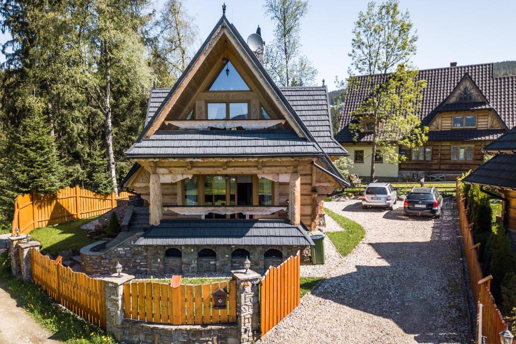 a house with a gambrel roof and a fence at Domek w Roztokach z widokiem na Tatry in Kościelisko