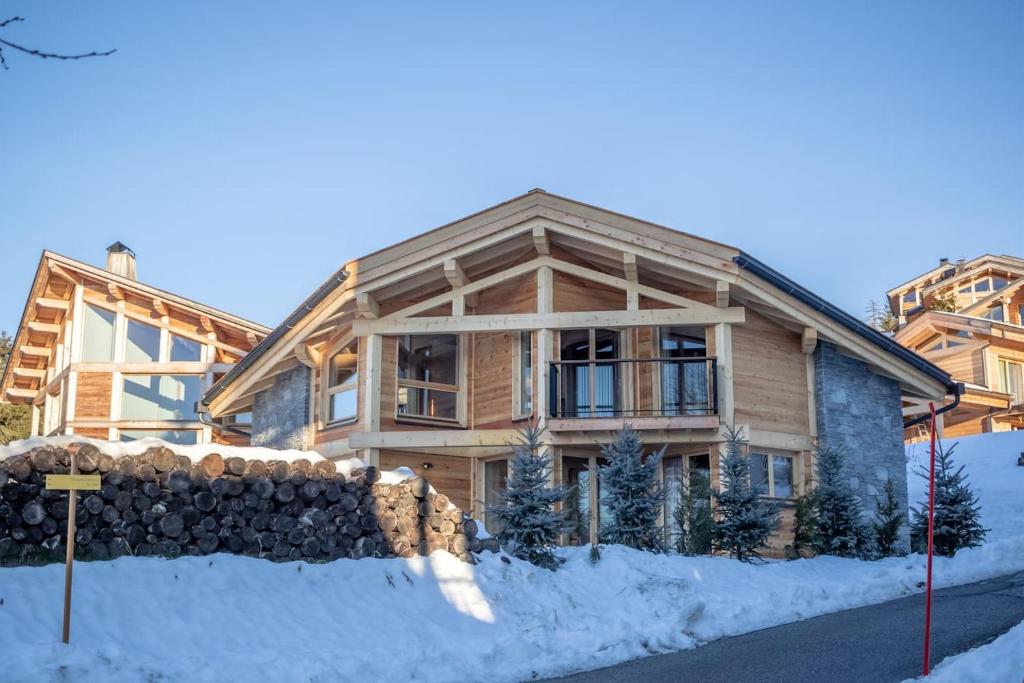 une grande maison en bois avec de la neige devant elle dans l'établissement Chalet Béla Vya, à Arc 1600