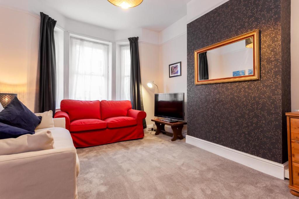 a living room with a red couch and a television at Gorgeous Town Centre Apt with Courtyard Garden in Bournemouth