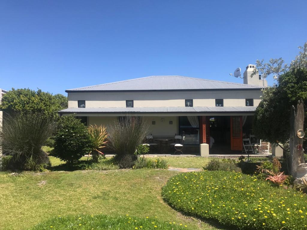 una casa blanca con un jardín delante en Fraai Uitzicht Struisbaai, en Struisbaai
