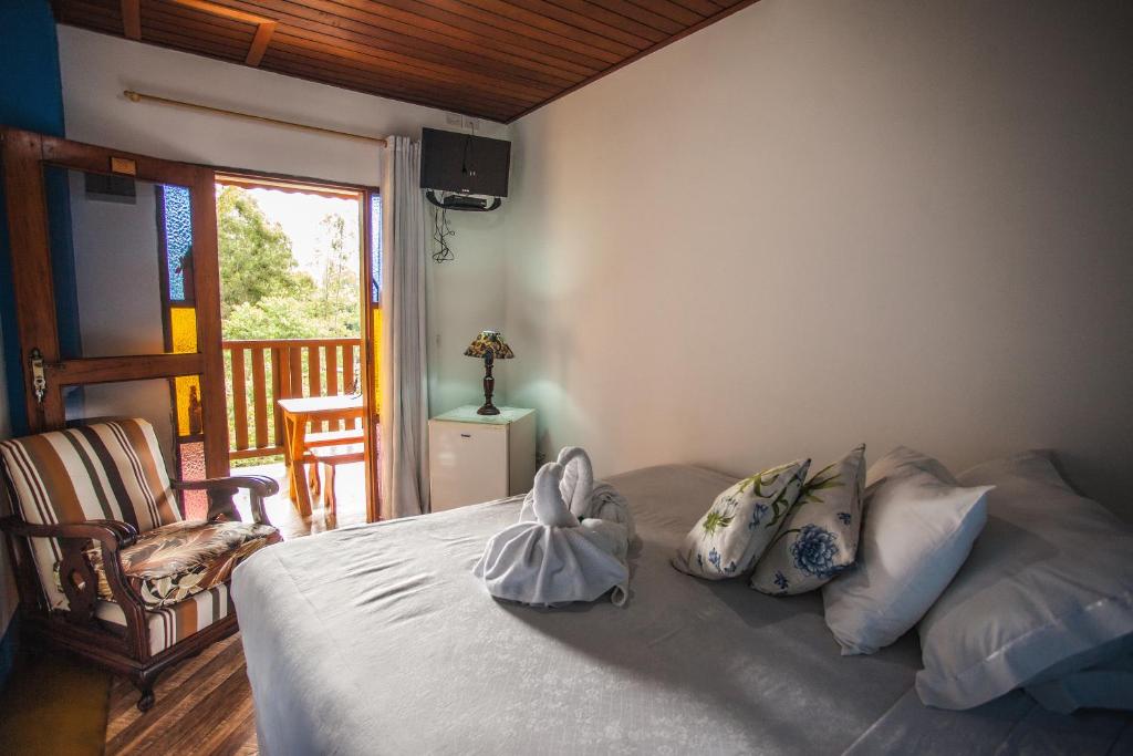 a bedroom with a bed with two stuffed animals on it at Pousada Refugio dos Palmares in São Bento do Sapucaí