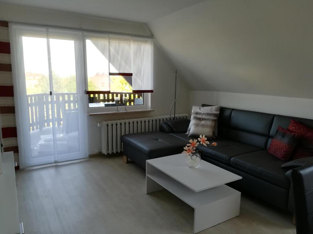 ein Wohnzimmer mit einem schwarzen Sofa und einem Tisch in der Unterkunft Ferienwohnung im Harz in Wienrode