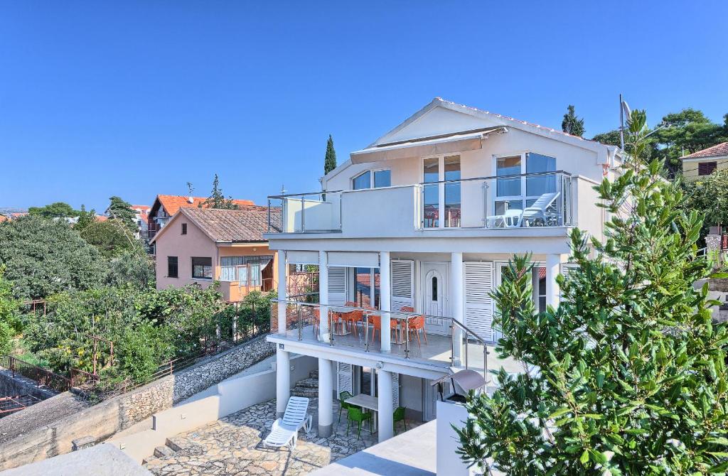 a large white house with a balcony and trees at Apartmani ATL in Rogoznica