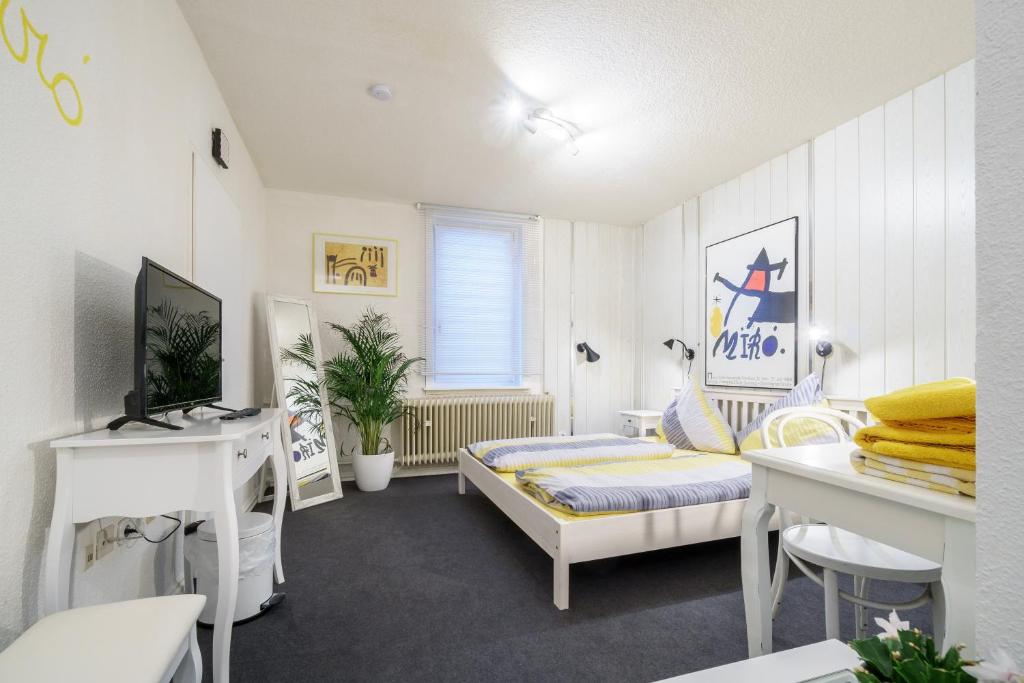 Dieses weiße Zimmer verfügt über ein Bett, einen Schreibtisch und einen Tisch. in der Unterkunft Hotel Tusculum in Marburg an der Lahn