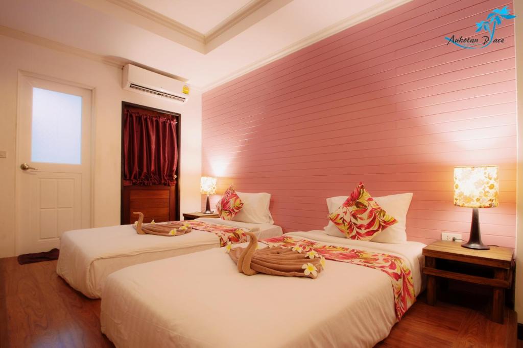 two beds in a room with a pink wall at Aukotan Place in Koh Tao