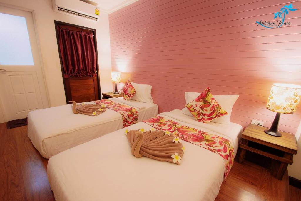 a room with two beds and a pink wall at Aukotan Place in Koh Tao