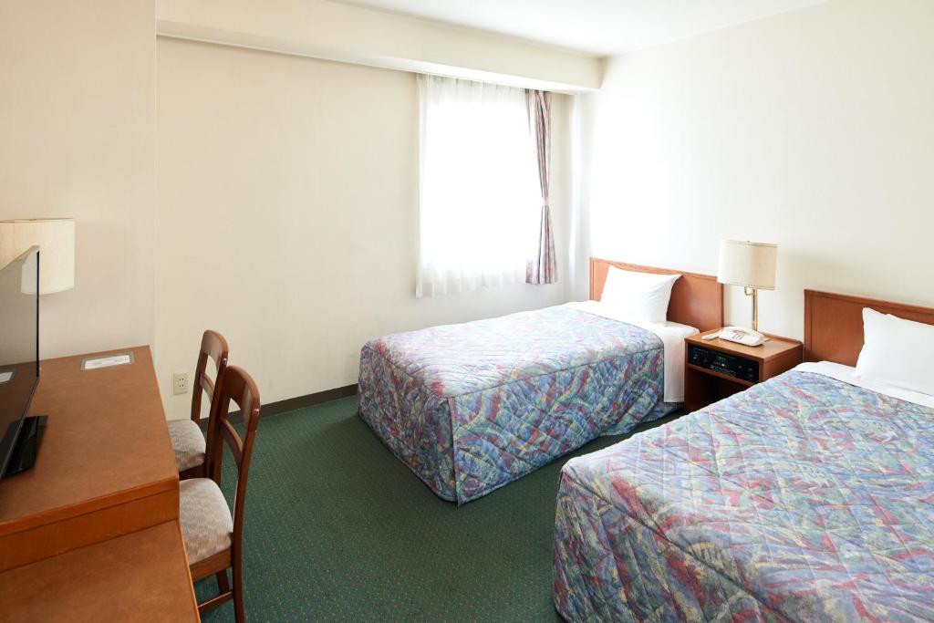 a hotel room with two beds and a desk at Marroad Inn Hachioji in Hachioji