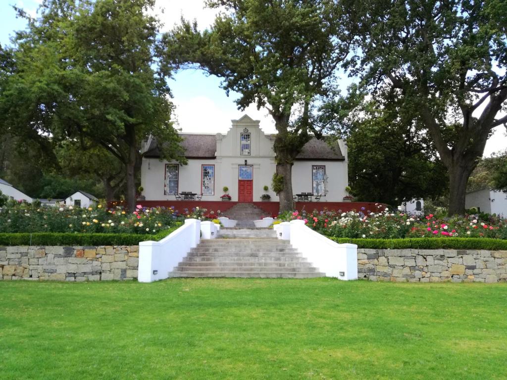 a white house with stairs and flowers in front at Diamant Estate in Paarl