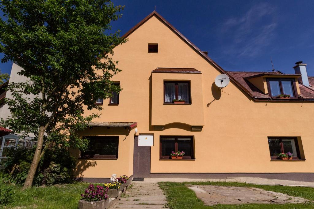 una casa amarilla con dos ventanas y un árbol en Penzion U Krotkých - Vyšší Brod en Vyšší Brod