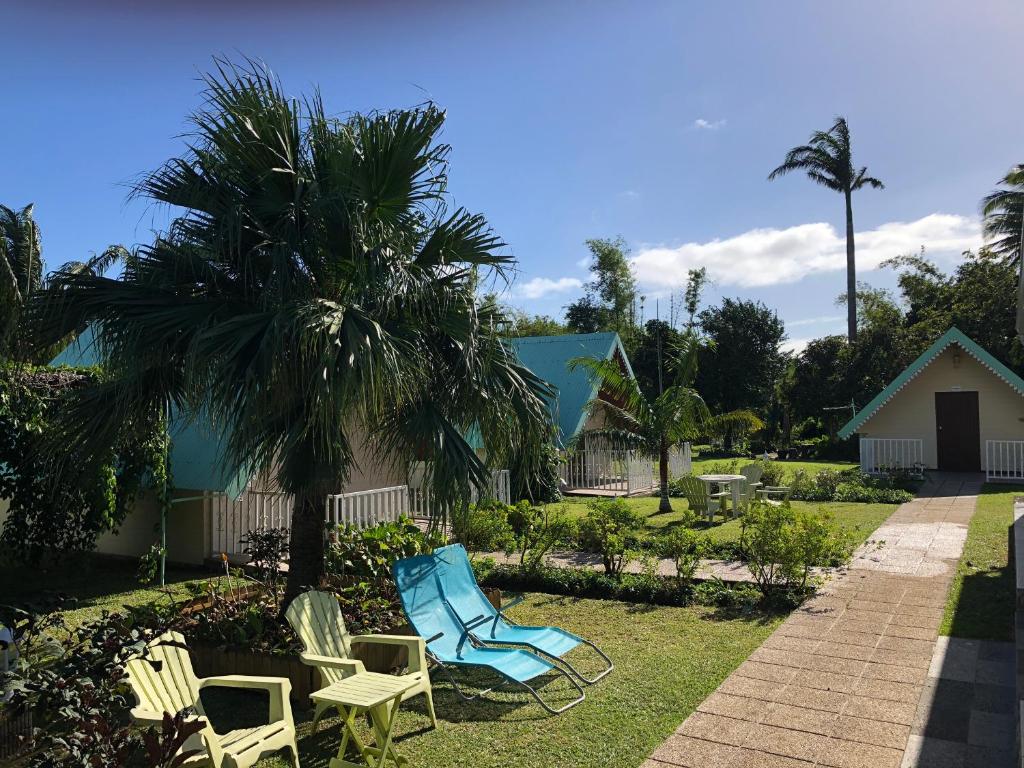 a group of chairs and a palm tree in a yard at Les Résidences du Niagara in Sainte-Suzanne