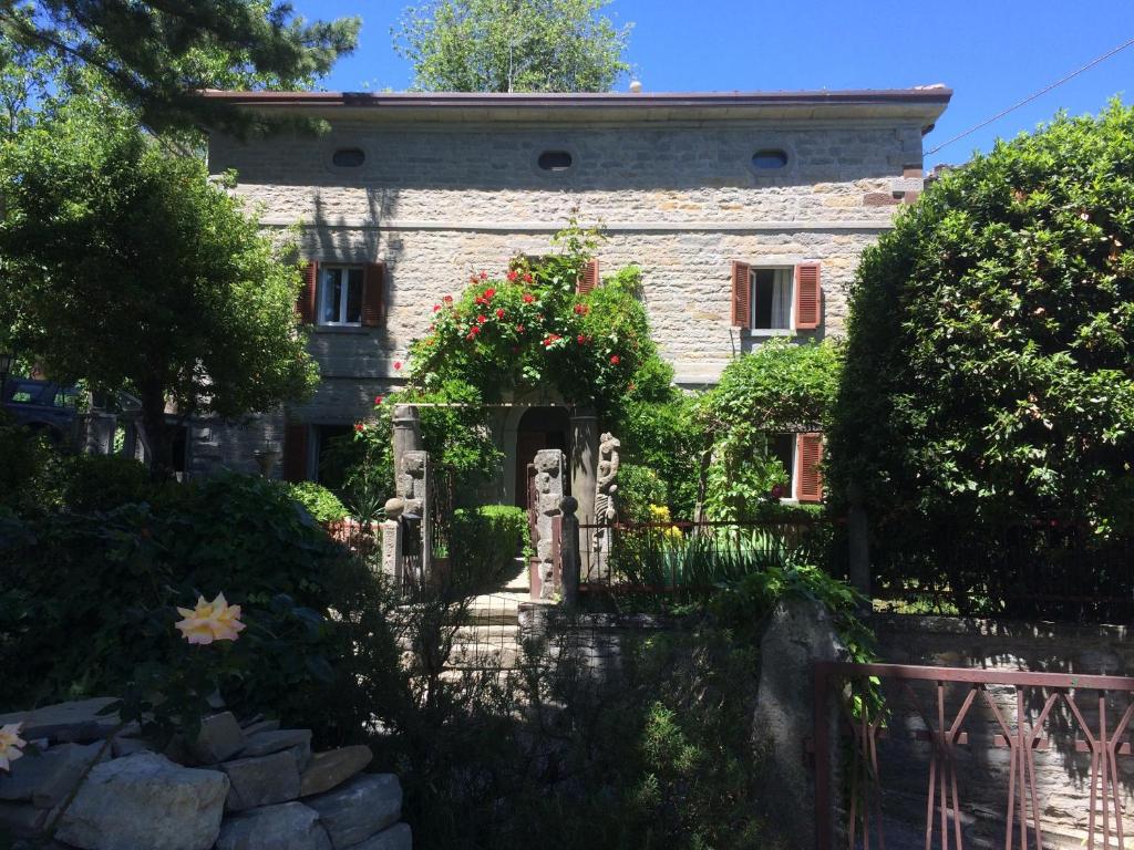 ein altes Steinhaus mit einem Zaun und Blumen in der Unterkunft Casa Kuraj in Sestino