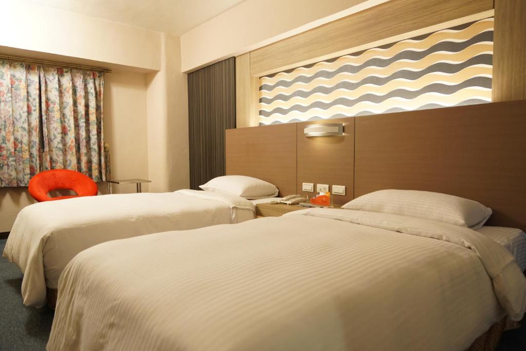a hotel room with two beds and a window at Ying Dai Hotel in Tainan