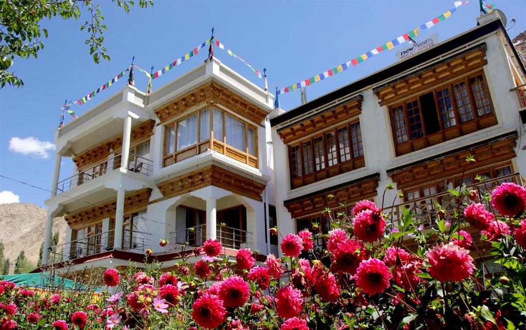 un edificio con flores rosas delante de él en New Moon Guest House, en Leh